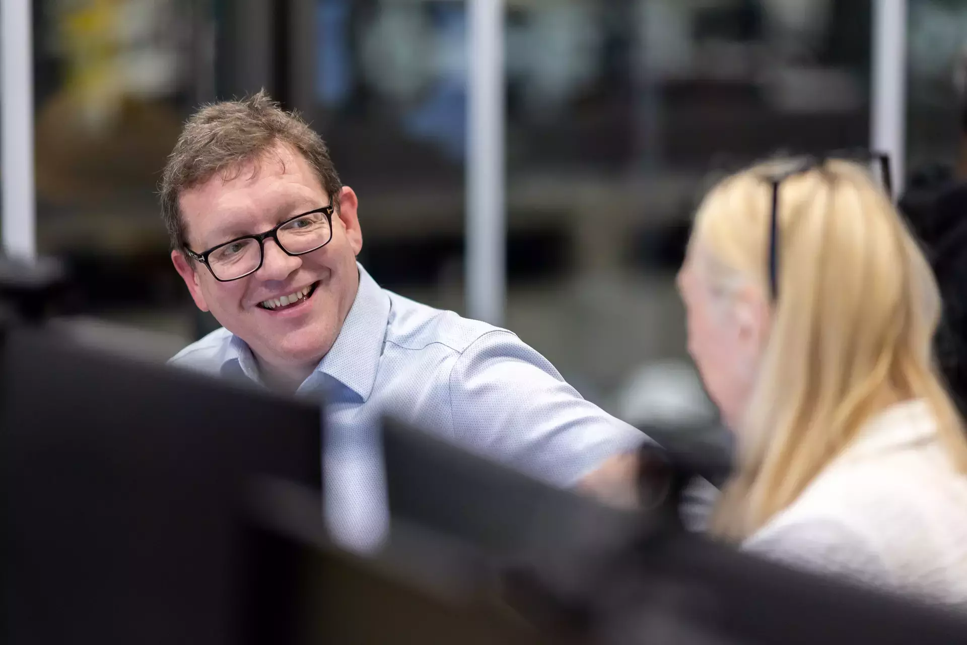 people_colleagues_talking_infront_of_computers_in_office