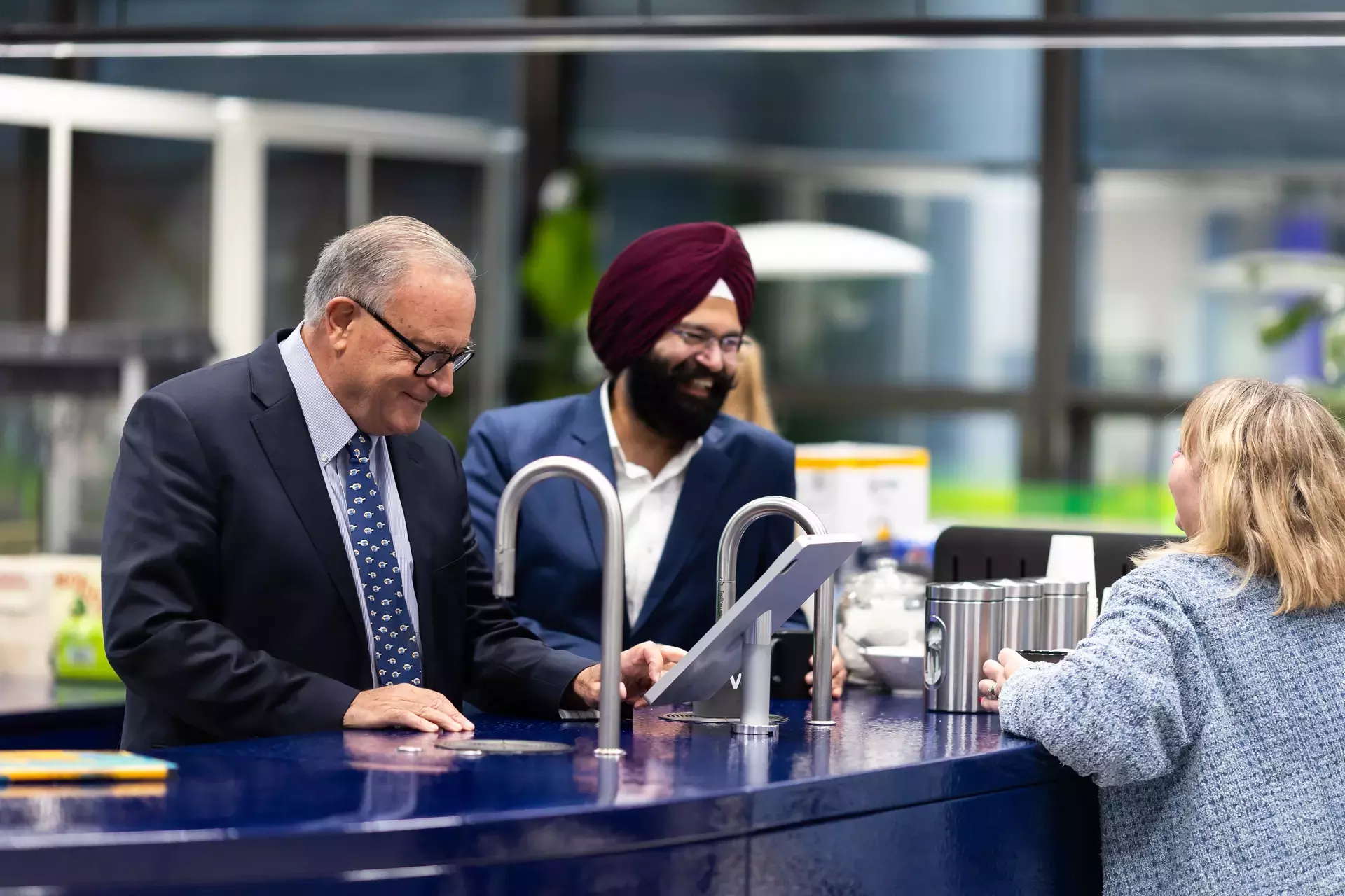 people_colleagues_talking_laughing_at_coffee_area_using_machine